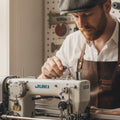 Man working on a sewing machine in a workshop setting