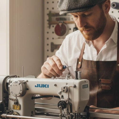 Man working on a sewing machine in a workshop setting